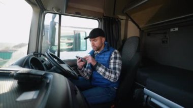 Kamyon şoförü kulübede oturuyor, geziye başlamadan önce güzergahı incelemek için akıllı telefonuyla GPS kullanıyor..