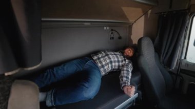 Kamyon şoförü dinlenme molasından sonra kamyonun içindeki yatağın içinde uyanıyor. Yolda yaşam ve taşımacılık rutini yakalandı.