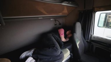Bir kadın kamyon şoförü mola sırasında kamyon kabininde uykusundan uyanıp yolda yeni bir güne hazırlanıyor..