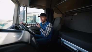 Kamyon şoförü elinde telsizle kulübede oturmuş lojistiği koordine ediyor ve teslimat için hazırlanıyordu. Arkaplanda düzenli çalışma alanı.