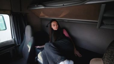 Kamyon şoförü kadın kamyon kabinindeki yatağında dinleniyor. Mola sırasında uyumaya hazırlanıyor. Kamyonculukta huzurlu bir an.