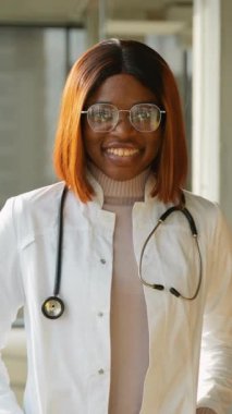 Klinikte steteskopu olan beyaz önlüklü Afro-Amerikalı kadın doktor..