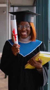 Siyah şapkalı ve cüppeli kararlı bir mezun, elinde kitap ve diplomayla, akademik başarıyı ve parlak bir geleceği simgeleyen kapalı bir alanda yürüyor..