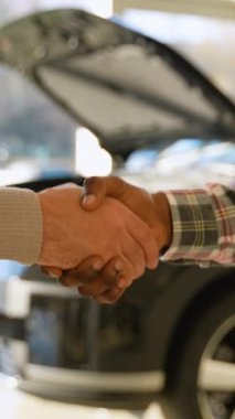 Bir araba tamircisi ile bir servis merkezindeki müşteri arasındaki el sıkışma, araba tamirinden sonra güven ve memnuniyeti simgeliyor..