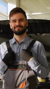 Atölyedeki kendinden emin bir tamirci kaputu açık siyah bir SUV 'un önünde duruyor. Araç bakımı ve teşhisi için hazır..