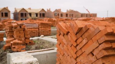 Kırmızı tuğlalar ve beton temellerle dolu bir inşaat sahası, tamamlanmamış konak binaları ve arka planda bir vinç görünüyor..
