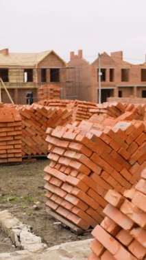 Kırmızı tuğlaları ve beton temelleri olan, tamamlanmamış konak binaları ve arka planda bir vinç olan bir yerleşim yeri..