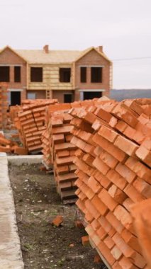 Kırmızı tuğlalar ve beton temellerle dolu bir inşaat sahası, tamamlanmamış konak binaları ve arka planda bir vinç görünüyor..