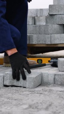 Donanma üniformalı bir inşaat işçisi kaldırıma kaldırım taşı döşeyerek düzgün bir dizilim ve istikrar sağlar..