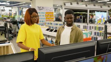 Bir Afrikalı Amerikalı çift, bir elektronik mağazasından televizyon alırken ekranın boyutunu, özelliklerini ve fiyatını tartışıyorlar..