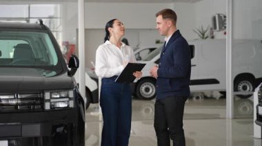 Profesyonel bir kadın araba satıcısı, bir galeride Kara Cuma satışında erkek müşteriye yeni bir araç seçmesinde yardımcı olur..