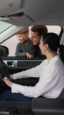 Mutlu bir aile, galeride yeni sağdan sürüş arabalarının özelliklerini inceler. Anne sürücü koltuğunda otururken, baba ve oğul izleyecek..