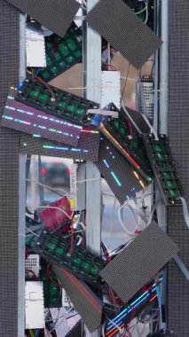 Parçalanmış LED panelleri, açık devreleri ve karmaşık kabloları olan, kentsel bir ayar içindeki hasarlı elektronik bileşenleri ortaya çıkaran, parçalanmış dijital bir reklam panosunun ayrıntılı bir görüntüsü.
