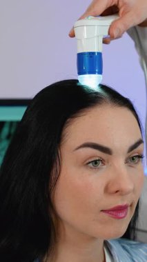 Bir trichologist dijital mikroskop kullanan bir kadın üzerinde saç analizi yapıyor. Bu prosedür kepek, sebora, saç dökülmesi ve genel olarak kafa derisi sağlığının teşhis edilmesine yardımcı oluyor..