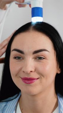 Bir kadın, dijital tanı cihazı kullanarak kafa derisini incelemek için bir trikoloğu ziyaret ediyor. Bu prosedür kepek, sebora, saç dökülmesi ve kafa sağlığının değerlendirilmesine yardımcı olur..