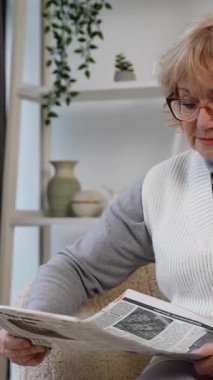 Gözlüklü yaşlı kadın rahat bir koltukta oturup gazete okuyor. Rahatlamış ve haberlerle meşgul görünüyor, evde sakin bir anın tadını çıkarıyor..