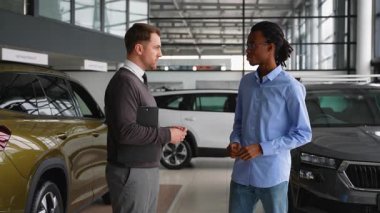 Bir araba satıcısı ve Afrikalı bir Amerikalı müşteri galeride el sıkışıyor, başarılı bir araba alımı ve anlaşmayı onaylıyor..