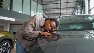 Bir adam galeride yeni arabasının kaputuna yaslanır, parlak tasarımına hayran kalır ve derin bir minnettarlıkla bitirir..