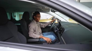 Afro-Amerikalı bir adam yeni aldığı arabasında oturuyor, galerideki Kara Cuma anlaşması için heyecanlı, yeni arabasının keyfini çıkarıyor..