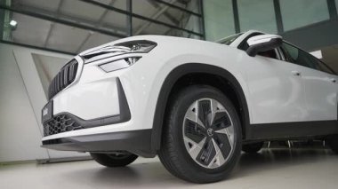 Bir galeri galerisinde yepyeni beyaz bir SUV 'un düşük açılı çekimi, gösterişli ön tasarımı, şık alaşım tekerlekleri ve modern otomotiv özellikleri sergileniyor..