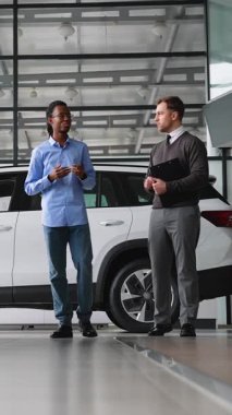 Bir araba satıcısı, bir galeride Afrikalı Amerikalı bir müşteriye yardım ediyor ve yeni bir araç alımında özel indirimler sunuyor..