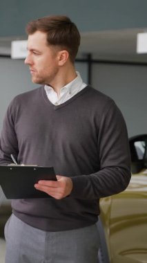 Profesyonel bir araba satıcısı, modern bir galeride araba envanterini, hipodrom satışlarını ve araba kullanımını kontrol etmek için dizüstü bilgisayar kullanır..