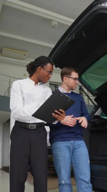 Bir araba satıcısı bir galeri içerisindeki bir müşteriye kargo alanı ve araç özelliklerinin altını çizerek satın almadan önce bir SUV 'nin bagaj kapasitesini açıklar..