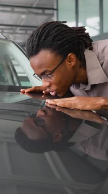 Mutlu bir adam galeride yeni arabasının kaputuna sarılıyor. Son aldığı araçtan duyduğu neşe ve heyecanı dile getiriyor..