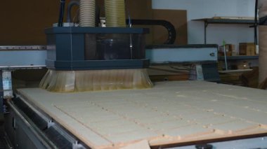 Otomatik CNC yönlendirici makine bir ahşap fabrikasında mobilya üretimi için MDF sayfasını küçük dikdörtgen parçalara ayırıyor..