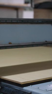 Bir ahşap üretim tesisinde özelleştirilmiş mobilya bileşenleri için MDF sayfasını küçük dikdörtgenlere ayıran CNC yönlendirici makinesinin yakın plan görüntüsü.