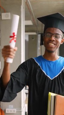 Şapka ve cübbeyle gülümseyen Afrikalı Amerikalı mezunlar, parlak, modern bir akademik alanda dururken gururla diploma ve kitap tutarlar..