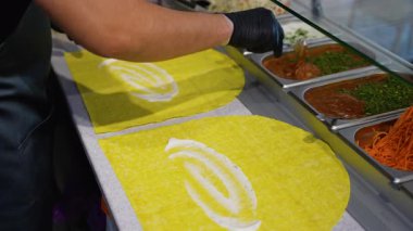 Hazır yemek reyonunda diyet dostu shawarma ve taze sebzeler için sarı tortilla üzerine sos döken şefin yakın çekimi..