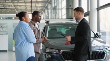 Profesyonel satış aracı özelliklerini Afro-Amerikan çifte sunuyor, otomotiv galerisi ayarlama konusunda uzmanlaşmış satın alma sürecine rehberlik ediyor.