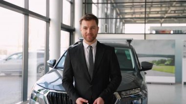 Profesyonel araba satıcısı güvenli bir şekilde araç anahtarını sunarken modern galeri galerisinde, başarılı otomotiv satışları etkileşiminin sinyalini veriyor.