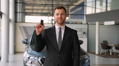 Profesyonel satıcı, satış mağazasının içinde yeni araba anahtarını sunuyor, çeşitli satın alma seçenekleri sunuyor ve potansiyel müşterilere sosyal yardımlar sunuyor