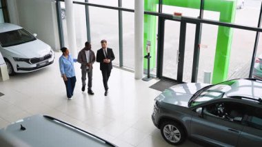 Profesyonel araba satıcısı, Afro-Amerikan bir çifte modern bir araba galerisinde rehberlik ve uzmanlık sunan yeni bir araç seçmesinde yardımcı oluyor.