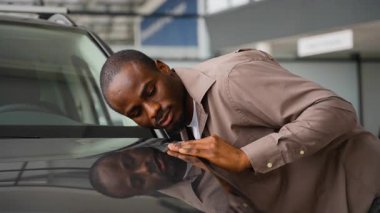 Hevesli müşteri bir galeride yeni bir arabanın kaputunu nazikçe okşuyor, zarif bitişine hayran kalıyor ve satın almayı düşünüyor.