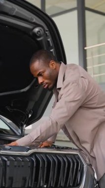 Potansiyel müşteri, bir satış şirketinde yeni bir arabanın motor bölmesini dikkatle inceliyor. Satın alma kararı vermeden önce detaylara olan ilgisini ve dikkatini gösteriyor.