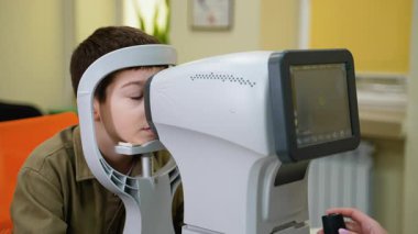 Tıp uzmanları, ileri otomatik fraksiyon teknolojisi kullanarak görme yetisini değerlendiren ve olası kırılma hatalarını tespit eden genç bir çocuk üzerinde kapsamlı bir göz muayenesi yapıyorlar.