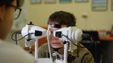 Uzman optometrist kapsamlı görme taraması yapıyor, genç pediatrik hasta ile birlikte özel tıbbi tanı ekipmanları kullanarak dürbün görme fonksiyonu ve göz sağlığını değerlendiriyor