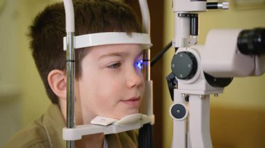 Pediatrik göz doktoru kapsamlı göz muayenesi yapıyor, çocuk hastalarının görüşünün ve göz sağlığının doğru değerlendirilmesi için özel teşhis ekipmanları kullanıyor