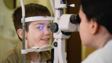 Modern tıp kliniğinde detaylı pediatrik vizyon değerlendirmesi için gelişmiş yarık lamba biyomikroskobu kullanarak kapsamlı göz muayenesi yapan profesyonel bir optometrist.
