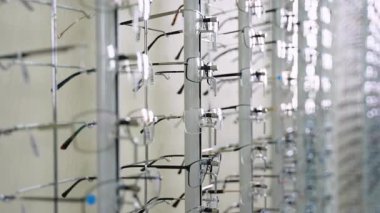 Optometrist, oftalmolog kabinesi veya gözlükçü dükkanında farklı şekil ve renklerde pek çok gözlük bulunan metal dönen ekran standı