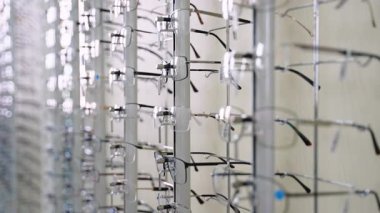Modern optik mağazada çeşitli gözlük seçimini gösteren metal döner ekran görüntüsü, görüş düzeltme ve moda aksesuar ihtiyaçları için birden fazla çerçeve, biçim ve lens türleri sunar