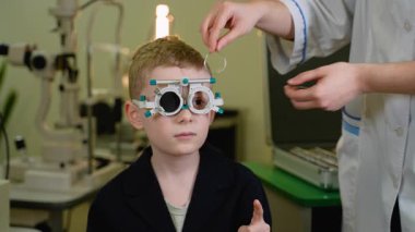 Oftalmolog deneme aşamasında olan bir çocuğun görme yetisini, görme keskinliğini ve göz testi, sağlık ve tıp konseptini inceliyor.