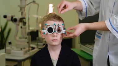 Modern tıbbi klinik ortamında uzmanlaşmış deneme çerçevesi kullanan genç hastalar için kapsamlı göz muayenesi yapan profesyonel bir optometrist