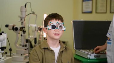Oftalmolog göz muayenesi sırasında bir çocuğun üzerine bir deneme çerçevesi yerleştirir, ve çocuk parmağını farklı yönlerde gösterir, ne gördüğünü gösterir.