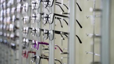 Bir optometrist dükkanındaki vitrin rafında düzenli olarak çeşitli gözlük modelleri, görüş düzeltmesi veya modaya uygun gözlük takmak isteyen müşteriler için geniş bir seçim sunuyor.