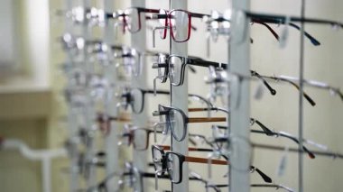 Optik bir mağazada çeşitli çerçeve biçimleri ve renkleri gösteren birden fazla gözlük, müşteriler için geniş bir seçim öneriyor