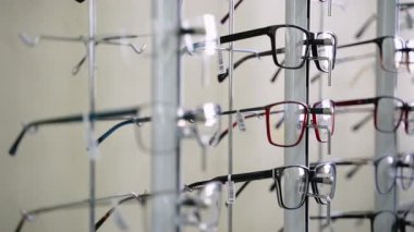 Optometrist mağazasında farklı şekillerde, boyutlarda ve renklerde birçok gözlük bulunan metal dönen ekran standı, mükemmel görüş için doğru çerçeveyi seçmek için ideal